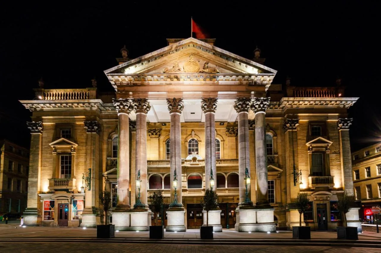 The County Hotel Newcastle's grand columned facade lit up at night on Neville Street