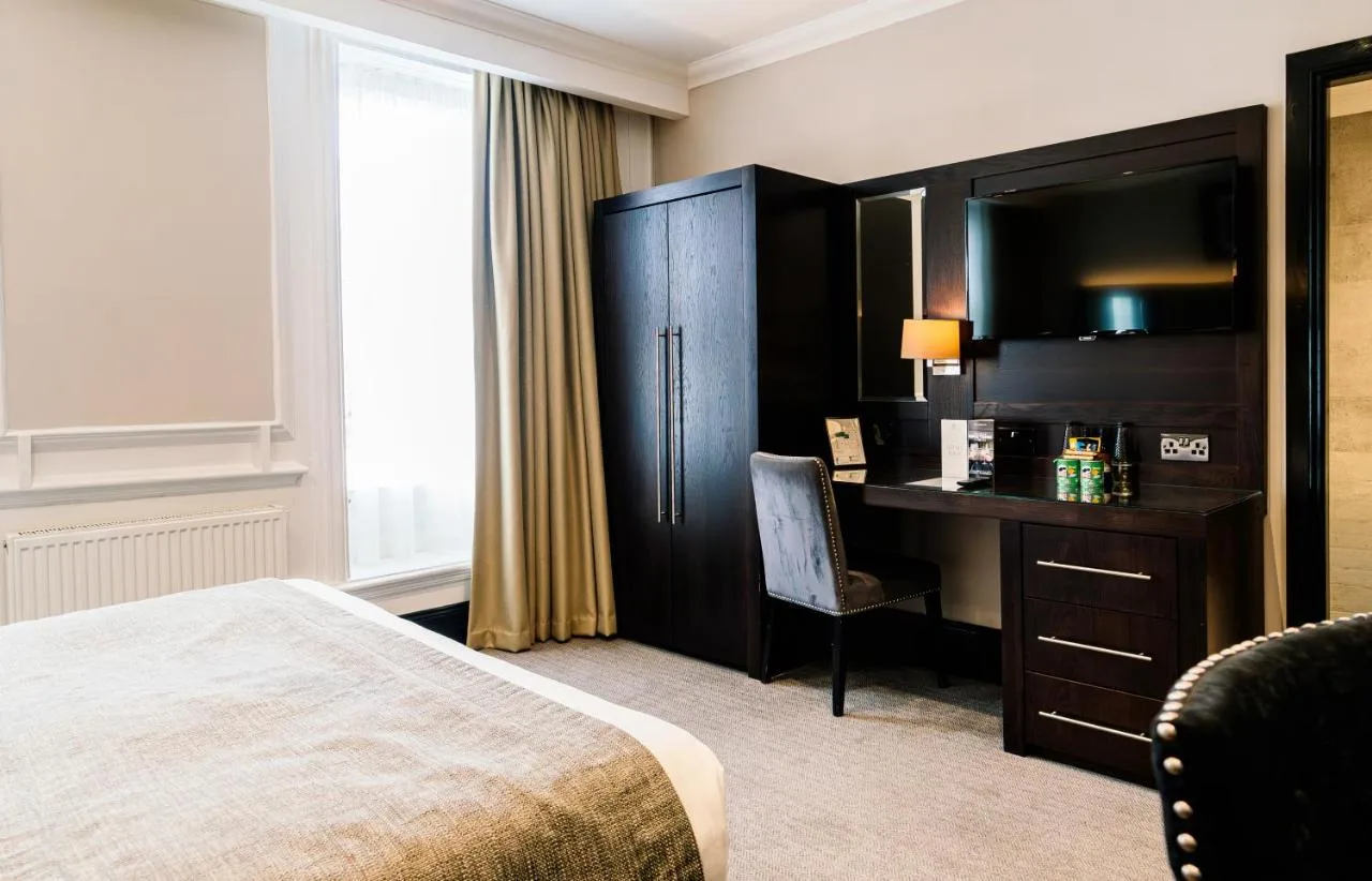 A comfortable guest room with a desk and television at The County Hotel Newcastle